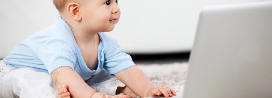 Beautiful small baby boy and a laptop.